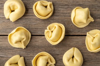 Ahşap masanın üzerinde pişmemiş cappelletti veya tortellini..