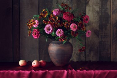 Çiçekler ve elmalarla dolu karanlık bir hayat sonbahar buketi kil sürahi ve meyve içinde