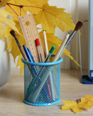 Kalemler ve fırçalar sonbahar kompozisyon kırtasiyesinde masanın üzerinde duruyor.