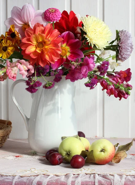 Φωτεινό Μπουκέτο Ντάλιες Μια Κανάτα Μήλα Και Δαμάσκηνα Στο Τραπέζι — Φωτογραφία Αρχείου