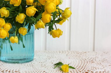 Trollius, mavi cam vazodaki sarı çiçekler dantel masa örtüsü fotokopi alanı