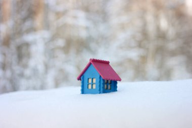 Ormandaki bir kar yığınında ahşap bir evin yerleşimi, bulanık bir kış geçmişi, pembe çatılı küçük mavi bir bina.