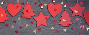 Ahşap arka planda kırmızı süslemeleri ve konfetileri olan yeni yıl afişi.