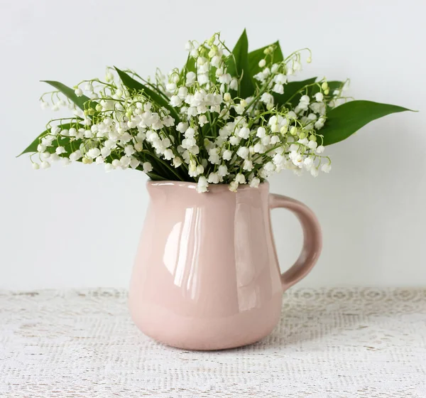 Béžový džbán s kyticí lilií z údolí. — Stock fotografie
