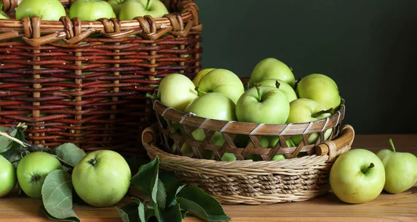 Manzanas verdes en cestas y sobre la mesa. — Foto de Stock