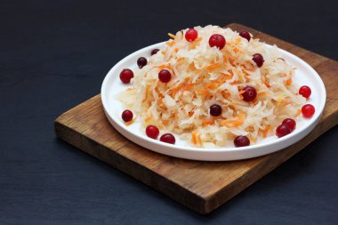 Koyu arkaplanda yaban mersinli lahana turşusu. Ev yapımı Rus yemeği. Laktik asit fermantasyonundan sonra havuç ve lahana salatası..