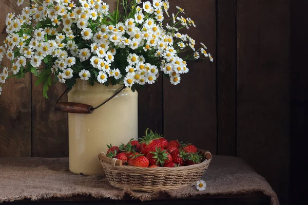 Land stilleben med prästkragar och jordgubbar. Stockbild
