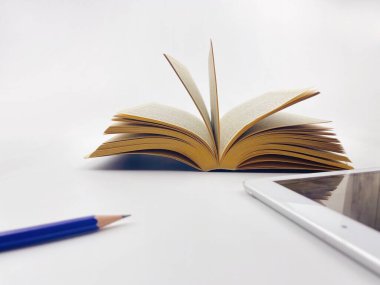 Beyaz arka plan bulanık kalem ve iPad üzerine eski bir kitabı açmak teknoloji ve eski moda arasında bir semboldür..
