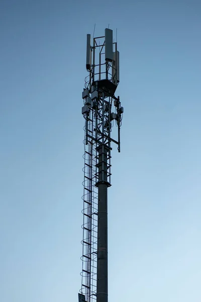 Wysoki filar z mobilnymi nadajnikami na tle błękitnego nieba. — Zdjęcie stockowe