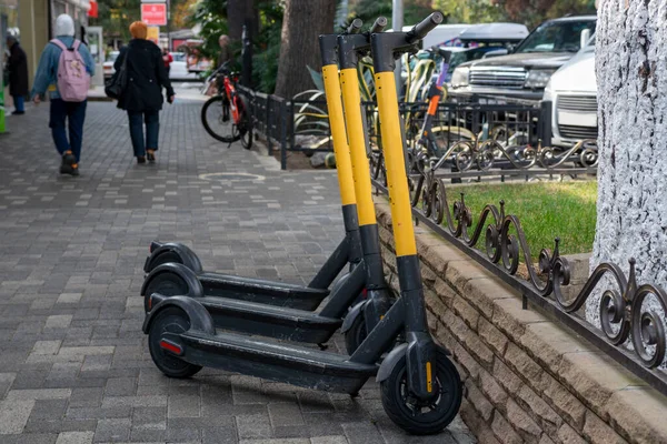 Three electric scooters stand at the edge of the sidewalk. — Stock Photo, Image
