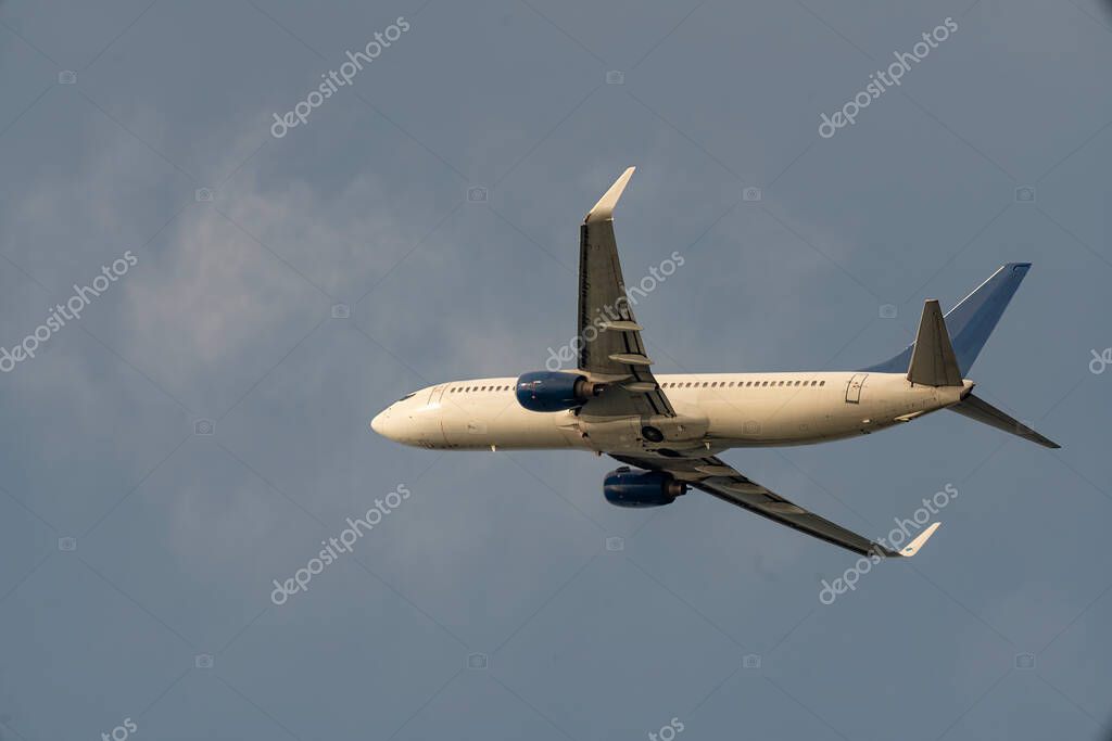 Passenger twin engine plane against the backdrop of a cloudy sky. Bottom view of a flying plane. Air transportation to resort towns.