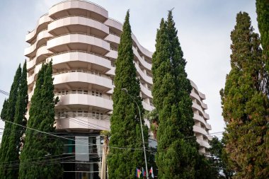 Tropikal ağaçların arkasındaki tatil köyünün binaları mavi gökyüzünün arka planına karşı..
