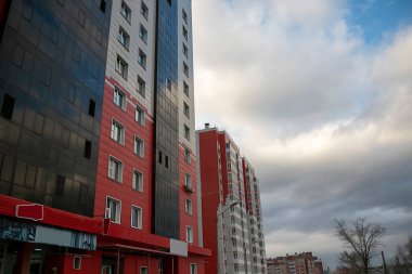 Mavi gökyüzünün arka planında bulutlu bir apartman binasının cephesi..