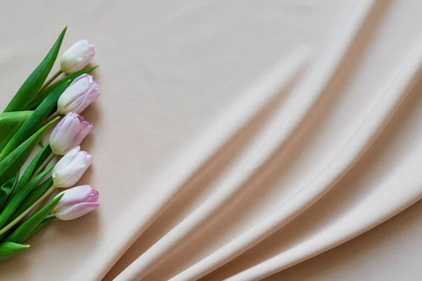 Bouquet primavera di tulipani rosa su tessuto beige con pieghe — Foto Stock