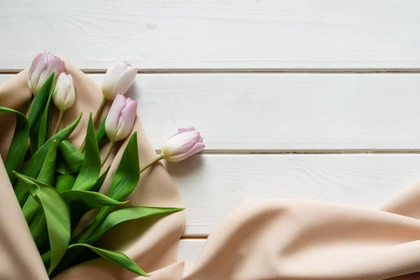 Bouquet primavera di tulipani rosa su tela beige su sfondo di legno — Foto Stock