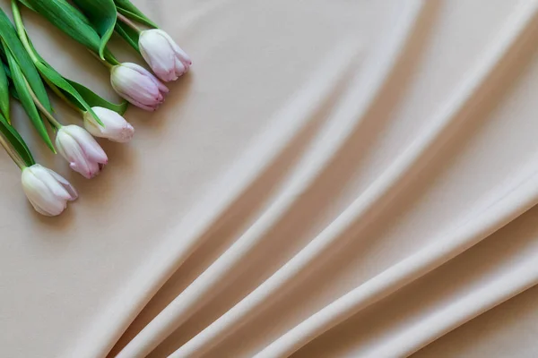 Bouquet primavera di tulipani rosa su tessuto beige con pieghe — Foto Stock