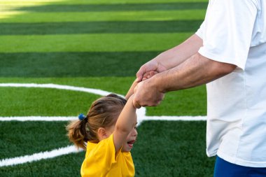 Kırpılmış yüzsüz, bütün vücutlu bir adamın kızın elini tutup döndürdüğü yan manzara.