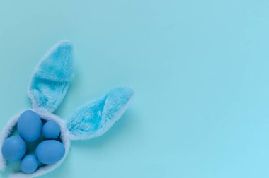 Mavi Paskalya yumurtalarının mavi arka planda mavi tavşan kulaklarından yapılmış mavi paskalya yumurtalarının üst görünümü 