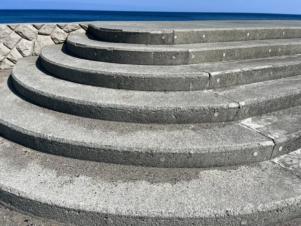 Curved gray concrete steps on a sea defence wall by the sea