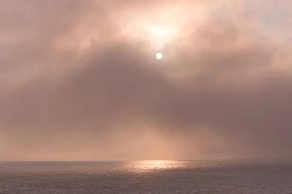 Pale sunlight filters through sea fog and reflects off the sea