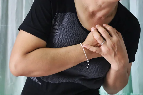 Asian women have chest pain. A woman wearing a black shirt put her hand on her chest that hurts or hurts her chest. Health care concept. Selective focus