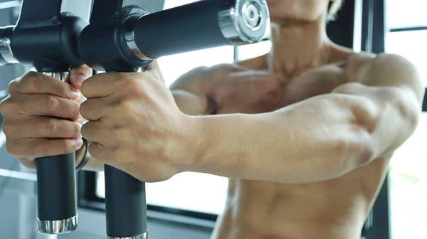 Hand holding a muscle building tool. Asian men use both hands to hold exercise bars to build shoulders and chest muscles in the gym or sports fitness center. Bodybuilding concept. Selective focus