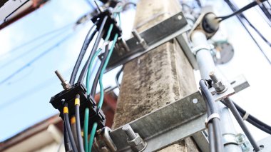 Direkte fiber optik kablo kıskaçları var. Telekomünikasyon ve zemin kabloları beton kutuplara, güneşli mavi gökyüzü arka planına monte edilir. Odaklan ve bir nesne seç.