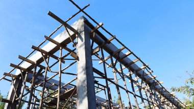 Beton sütunlar ve koltuk değnekleri. Altında beton kirişler olan evin yapısı parlak mavi gökyüzü arka planına karşı. seçici odak