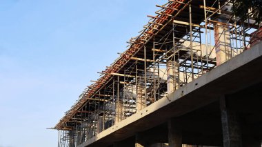 Metal yapı iskelesi ve biçimlendirme. Mavi gökyüzü arka planında inşa edilen yeni inşa edilmiş bir binanın, fotokopi alanı ile birlikte, resmi destek sistemi. Seçici odak