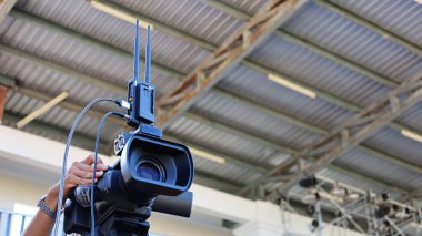 Video vericisi ve alıcısı. Stadyum tribününün arka planındaki kamera ve teknisyenlerin elindeki kablosuz video iletim seti fotokopi alanına sahip. Seçici odak