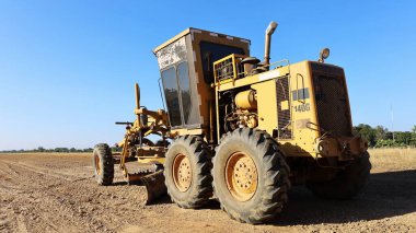 Yeni bir inşaatta derecelendirildim. Ağır ekipman Grader, mavi gökyüzü arka planında fotokopi alanı olan bir yol veya onarım yolu inşa ediyor. Seçici odak