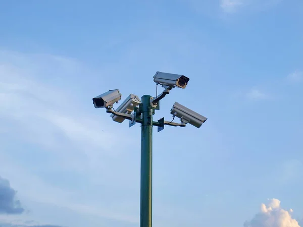 Güvenlik için yeşil sütunların CCTV 'si. Arka planda ince beyaz bulutlu mavi bir gökyüzü var..