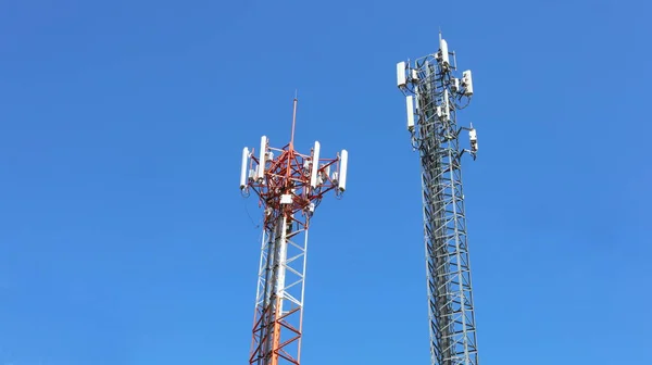 4G ve 5G Hücre Üssü. İkiz Üs Alıcı İstasyonu (BSC) radyo alıcı aygıtı cep telefonuyla cep telefonu kablosuz iletişimi ile bulutlu gökyüzü arkaplanındaki metal kulelerde kopya alanı ile.
