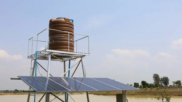 水箱和太阳能电池板 一个带有光伏电池的蓄水池抽水系统 在多云的天空背景下使用智能农场 并有复制空间 有选择的重点 — 图库照片