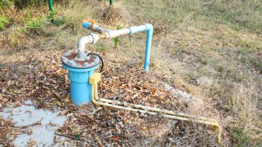 Yeraltı kuyularının mavi PVC boruları. Kirli bir beton zeminde fotovoltaik güçle çalışan ve kırsal alanda kuru yaprakları olan bir su altı pompasından pompalanan Artesian kuyusu. Seçici odak