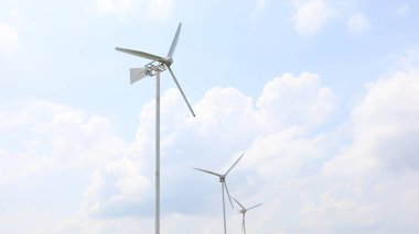 Sıra sıra rüzgar türbinleri. Yel değirmeni, beyaz bir gökyüzü arkaplanındaki bahçeyi fotokopi alanıyla süslüyor. Seçici odak