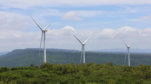 Wind power plant on the tower. Rows of large wind turbines for wind power generation in mountain background and bright blue sky with white clouds with copy space. Selective focus