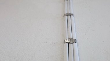 Duvardaki kablo klipsi. Alüminyum tel klipsi ve beyaz elektrik kablosu fotokopi alanı olan beton duvarda. seçici odak