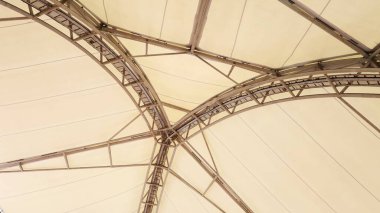 Old metal dome structure. The cream-colored tall dome has a triangular shape with arched steel columns in the bottom view in shallow focus with copy space.