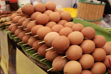 Izgara şiş yumurta. Baharatla karıştırılmış omletle yapılmış ızgara tavuk yumurtası, mangal kömürü sobasında ızgara, sığ görünümlü Tayland geleneksel marketinde sokak yemeği..