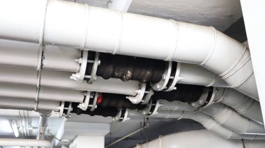 Tesisat borularını bağlamak için esnek lastik eklemi. Büyük binaların altındaki tesisat sistemlerindeki lastik eklemler ya da hortumlar sübvansiyonu önlemek ve kopya alanındaki titreşimleri azaltmak için. Seçici odak