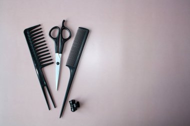 Bir kuaför için alet takımı. Siyah makas ve pembe arka planda bir tarak..