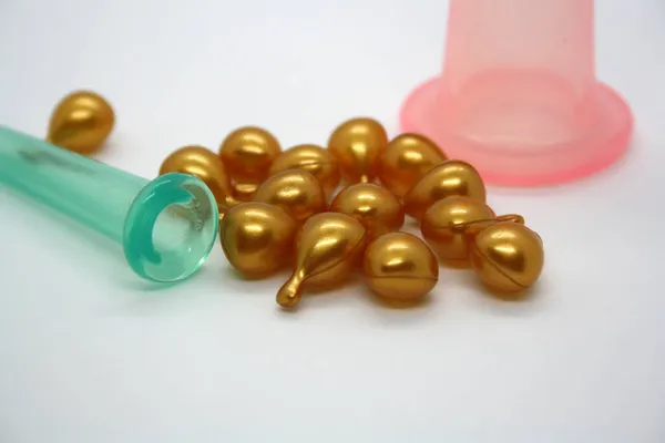 A jar for facial massage and gold capsules with oil. White background.