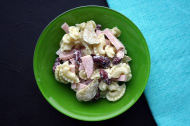 Makarna, jambon, fasulye ve salatalık turşusu. Belçika mutfağı. Siyah beyaz arka planda yeşil plaka.