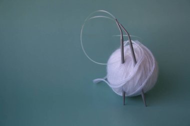 Kadınların hobisi. Tığ işi ve örgü. Masada beyaz iplik ve tığ işi iğneler var. Çalışma alanı.