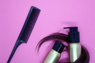 Açık kahverengi kadın saçı, pembe arka planda saç bakım ürünleri. Üst görünüm