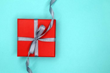 Kırmızı ve gri temalı hediye kutusu. Parlak kırmızı bir kutuyla hediye. Mavi arka plan. Sevgililer Günü kavramı. Üst Manzara. Düz yatıyordu.
