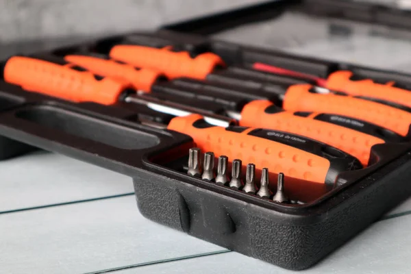 Depolama için siyah bir bavulda çeşitli eklentileri olan bir tornavida seti. Gri arkaplan