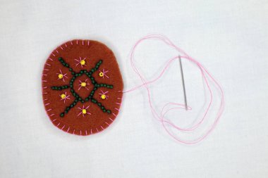 Keçeden yapılmış bir kaplumbağanın kabuğunda boncuklu nakış. Çocuklarla nakış işi.