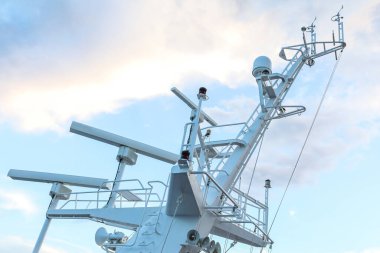 Ship structures, masts, antennas, funnel, ship wheelhouse against the blue sky and clouds. Vessel traveling at ocean.